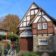 Fachwerkhaus mit Blumenbeet davor, Heimatmuseum Rehburg bei sonnigem Wetter und blauem Himmel.