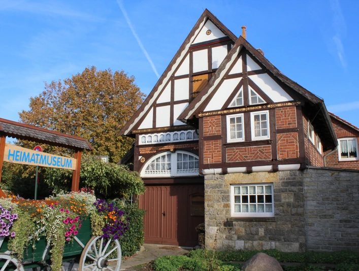 Fachwerkhaus mit Blumenbeet davor, Heimatmuseum Rehburg bei sonnigem Wetter und blauem Himmel.