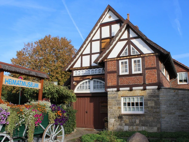 Heimatmuseum Rehburg Fachwerkhaus mit Blumenbeet davor, Heimatmuseum Rehburg bei sonnigem Wetter und blauem Himmel.