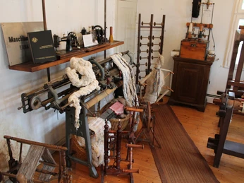 Heimatmuseum Rodewald Innenraumansicht eines traditionellen Museums mit alten Webstühlen und historischen Spinnrädern.
