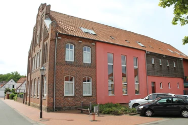 Backsteinfassade des Heimatmuseums Stolzenau mit modernen Anbauten und geparkten Autos davor.