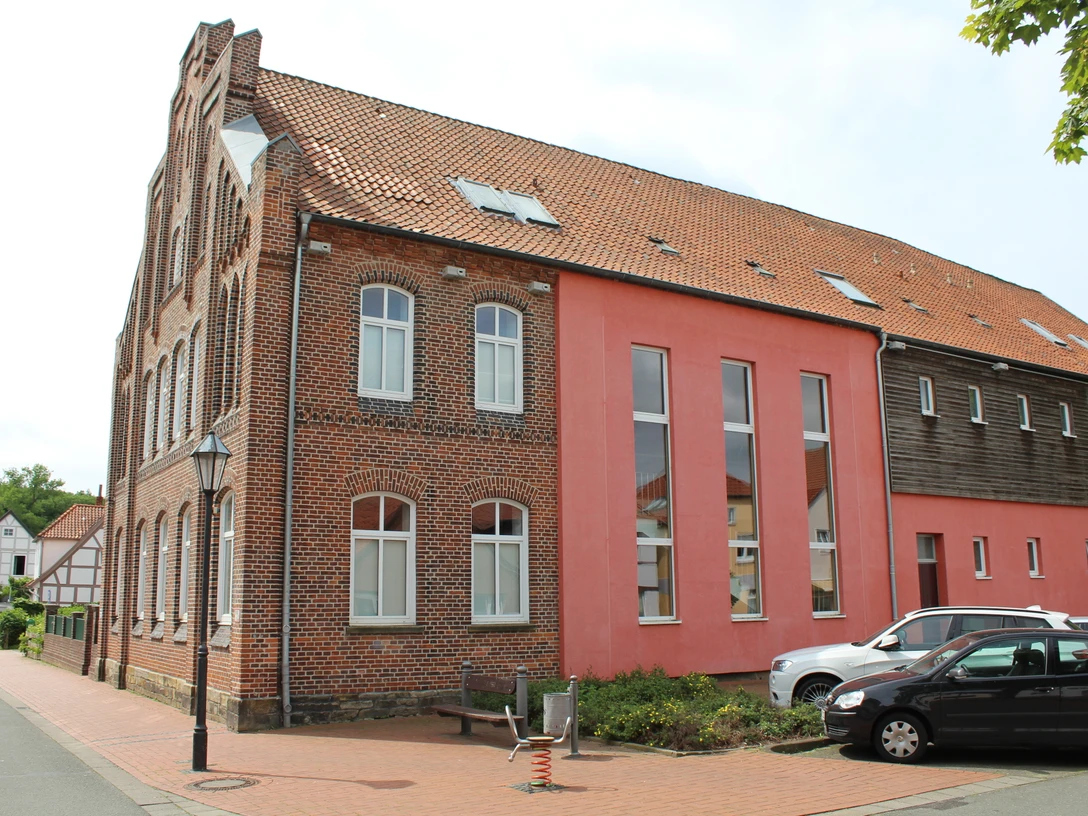 Backsteinfassade des Heimatmuseums Stolzenau mit modernen Anbauten und geparkten Autos davor.
