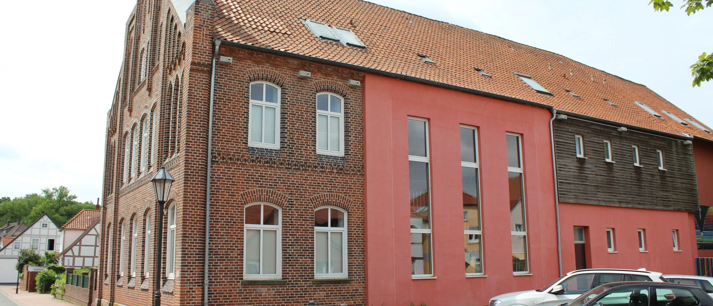 Backsteinfassade des Heimatmuseums Stolzenau mit modernen Anbauten und geparkten Autos davor.