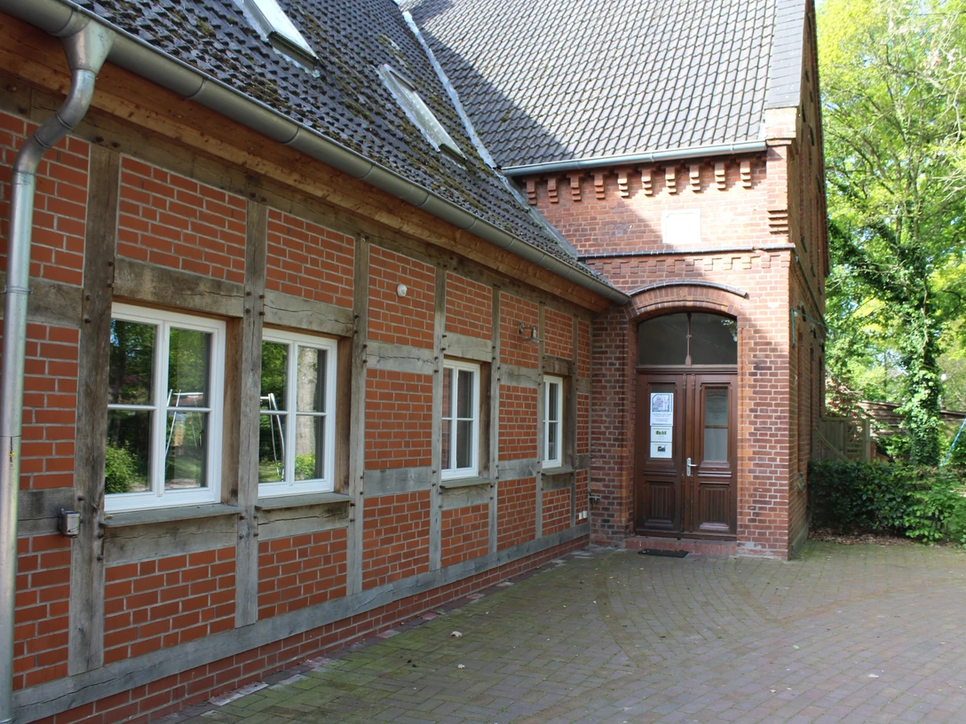 Heimatstube Schweringen Fachwerkgebäude mit roten Ziegeln und weiß eingerahmten Fenstern in ländlicher Umgebung.