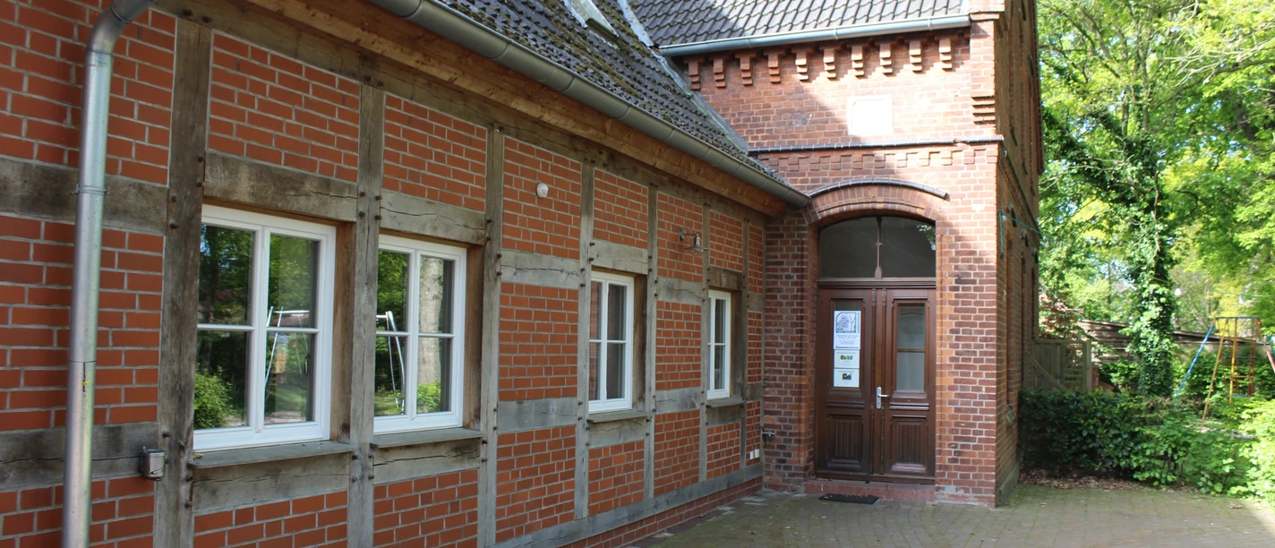 Heimatstube Schweringen Fachwerkgebäude mit roten Ziegeln und weiß eingerahmten Fenstern in ländlicher Umgebung.