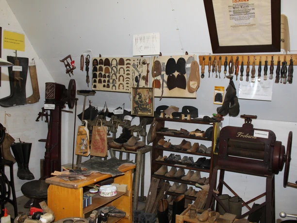 Heimatstube Wietzen Historische Werkstatt mit alten Schuhmacherwerkzeugen, Regalen voller Modelle und traditionellem Equipment.