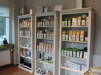 Tee-Shop Hiller Regale mit verschiedenen Teeverpackungen und Teezubehör in einem lichtdurchfluteten Raum eines Tee-Ladens.