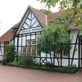 Fachwerkgebäude mit gepflegtem Garten und Schildern, zeigt Hochzeitsbahnhof Lavelsloh in Niedersachsen.