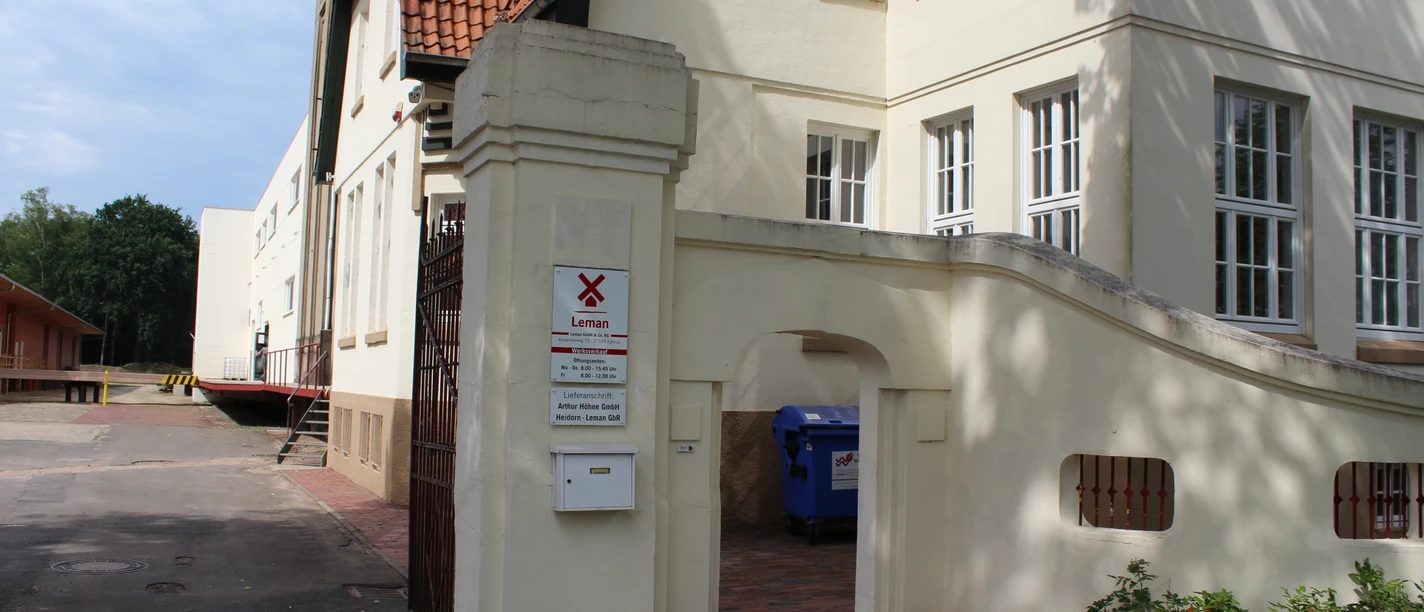 Eingang Senffabrik Eystrup Indgang med murstensbue til den historiske Eystrup Sennepsfabrik, omgivet af hvide bygninger.