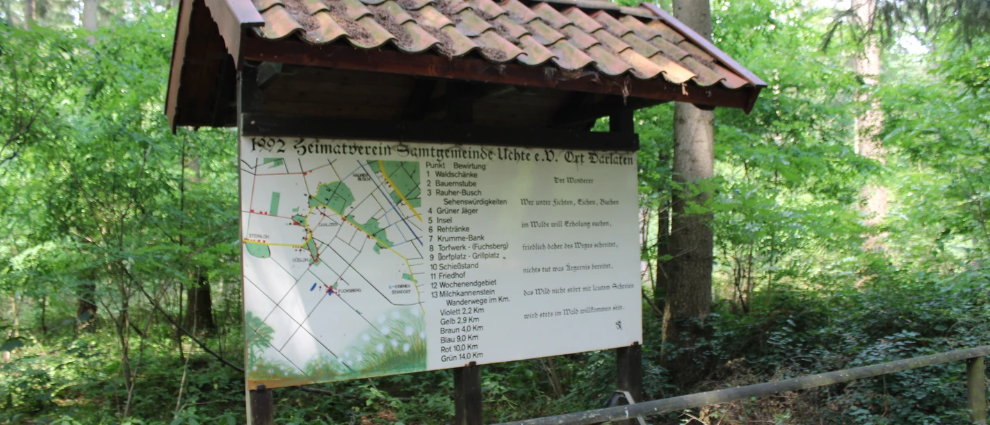 Die Insel in Darlaten Informationstafel des Heimatvereins Samtgemeinde Uchte e.V. im Wald von Darlaten, umgeben von Bäumen.