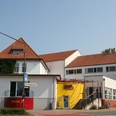 KASCH - Kulturhaus Alter Schützenhof Kulturhaus mit rotem Ziegeldach und gelber Eingangsfassade; moderne Architektur und zweckmäßig.