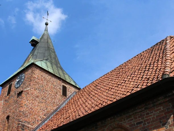 Kirche Binnen Backsteinkirche mit spitzem Kupferturm und Uhr vor blauem Himmel; markantes Beispiel norddeutscher Baukunst.