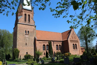 Kirche Magelsen Historische Backsteinkirche mit markantem Turm und grüner Umgebung an einem klaren blauen Himmel.
