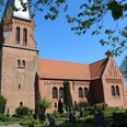 Kirche Magelsen Historische Backsteinkirche mit markantem Turm und grüner Umgebung an einem klaren blauen Himmel.