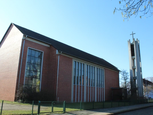 St. Bernwardkirche Backsteinkirche mit großen Fenstern und freistehendem Glockenturm, markant durch das Kreuz.