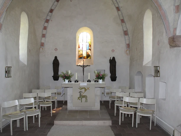 Kirche St. Cosmae et Damiani Hassel Altarraum Ein lichtdurchfluteter Altarraum mit Kreuz, flankiert von Statuen, mit weißen Stühlen umringt.