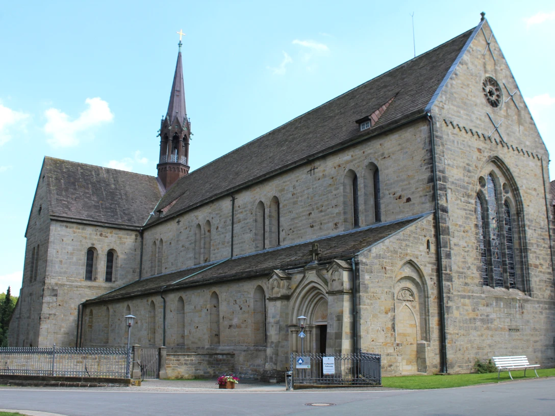 Kloster Loccum Romanische Fassade des Klosters Loccum mit hohen Fenstern und einem spitzen Turm bei klarem Himmel.Romanesque façade of Loccum Abbey with high windows and a pointed tower under a clear sky.Loccum-klostrets romanske facade med høje vinduer og et spidst tårn under en klar himmel.Romaanse gevel van de abdij van Loccum met hoge ramen en een spitse toren onder een heldere hemel.