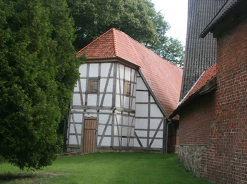 Fachwerkkirche Kloster Schinna im Grünen, mit rotem Ziegeldach und Fachwerkwänden, umgeben von Bäumen.Schinna Monastery half-timbered church in the countryside, with a red tiled roof and half-timbered walls, surrounded by trees.Schinna kloster er en bindingsværkskirke på landet med rødt tegltag og bindingsværksmure, omgivet af træer.Klooster Schinna Vakwerkkerk op het platteland, met een rood pannendak en vakwerkmuren, omringd door bomen.