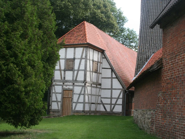 Schinna Monastery half-timbered church in the countryside, with a red tiled roof and half-timbered walls, surrounded by trees.