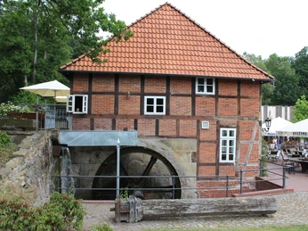 Historische Wassermühle aus Backstein mit Fachwerkakzenten, rotem Ziegeldach und intaktem Mühlrad.Historic brick watermill with half-timbered accents, red tiled roof and intact mill wheel.Historisk vandmølle i mursten med bindingsværk, rødt tegltag og intakt møllehjul.Historische bakstenen watermolen met vakwerkaccenten, rood pannendak en intact molenrad.