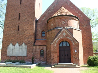 Kapelle Schweringen Backsteinkapelle mit markantem Rundbogenportal und dekorativen Fenstern, umgeben von Bäumen im Frühling.