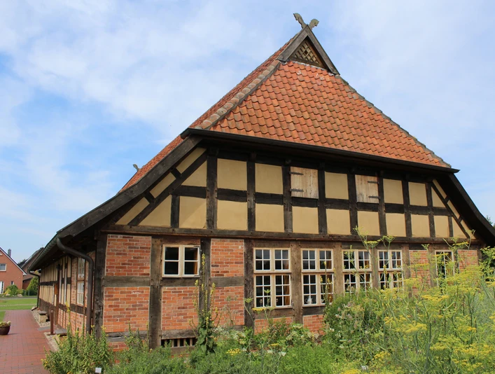 Kulturgut Ehmken Hoff in Dörverden Fachwerkhaus mit roten Ziegeln und steilem Dach vor blauem Himmel, umgeben von grünem Garten.