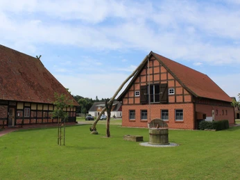 Brunnen am Ehmken Hoff Fachwerkgebäude mit freiem Brunnen auf gepflegter Grünfläche unter blauem Himmel im Ehmken Hoff.