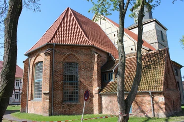 Kulturzentrum Martinskirche Hoya Backsteinkirche mit roten Dachziegeln und gotischen Spitzbogenfenstern, umgeben von Bäumen und Wiese.