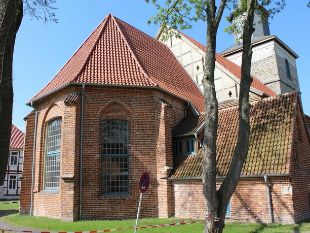 Kulturzentrum Martinskirche Hoya Backsteinkirche mit roten Dachziegeln und gotischen Spitzbogenfenstern, umgeben von Bäumen und Wiese.