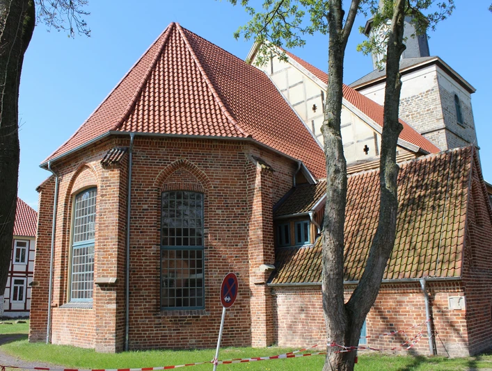 Kulturzentrum Martinskirche Hoya Backsteinkirche mit roten Dachziegeln und gotischen Spitzbogenfenstern, umgeben von Bäumen und Wiese.