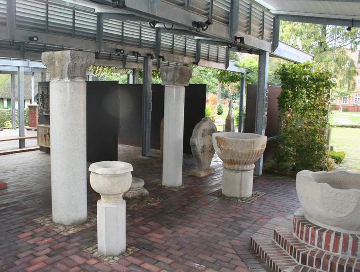 Steingefäße Lapidarium Steingefäße und Säulenreste unter einem überdachten Bereich auf gepflastertem Boden bei Tageslicht.