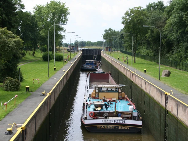 Frachtschiffe passieren die Schleuse Landesbergen entlang eines von Bäumen flankierten Kanals.