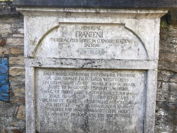 Steinrelief mit lateinischem Text, eingerahmt von einer antiken Grabplatte in verwittertem Zustand.