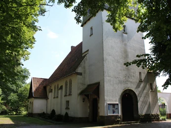 Kirche Raddestorf Kirche Raddestorf aus Backstein im gotischen Stil, umgeben von Bäumen, mit einem markanten Turm.