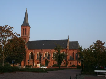Kirche Thedinghausen Backsteinkirche in Thedinghausen vor klarem Himmel, umgeben von Bäumen, mit markantem Turm.