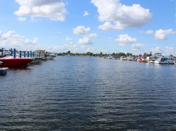 Eine weitläufige Marina mit anlegenden Booten und Yachten unter einem blauen Himmel mit Wolken.