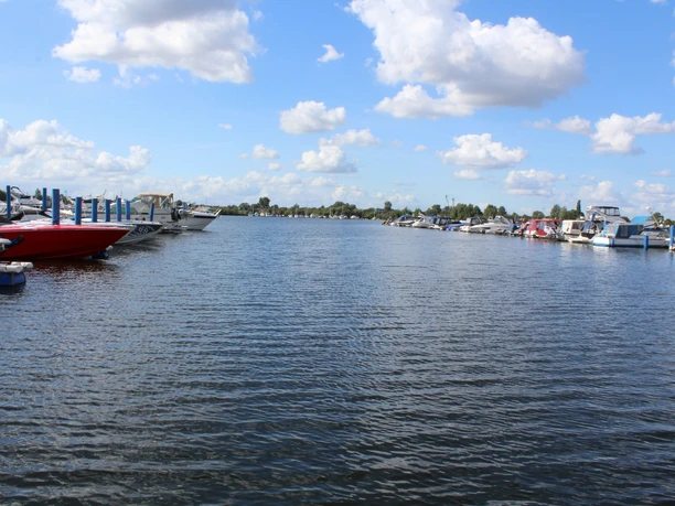 Eine weitläufige Marina mit anlegenden Booten und Yachten unter einem blauen Himmel mit Wolken.