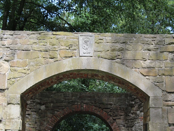 Mühlenruine Rehburg Alte Steinmauer einer Mühlenruine von Bäumen umgeben; Relief mit Wappen überbogenem Eingang.