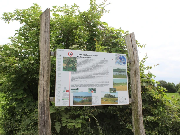 Naturlehrpfad Im Röden Stolzenau Informationsschild über den Naturlehrpfad Im Röden Stolzenau zwischen zwei Holzpfosten vor grüner Vegetation.