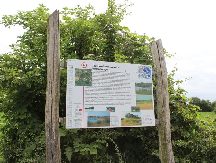 Naturlehrpfad Im Röden Stolzenau Informationsschild über den Naturlehrpfad Im Röden Stolzenau zwischen zwei Holzpfosten vor grüner Vegetation.