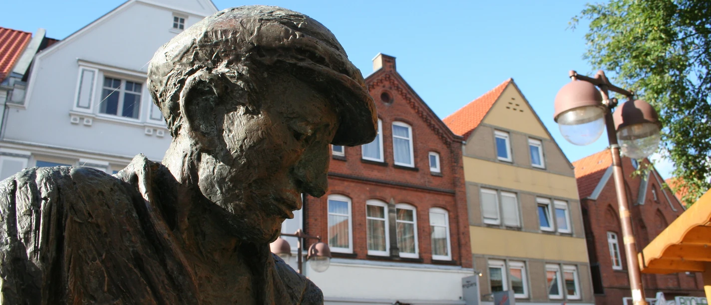 Nienburger Glasbläser Bronzestatue eines Glasbläsers in Nienburg, umrahmt von historischen Gebäuden im Hintergrund.