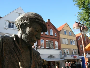 Nienburger Glasbläser Bronzestatue eines Glasbläsers in Nienburg, umrahmt von historischen Gebäuden im Hintergrund.