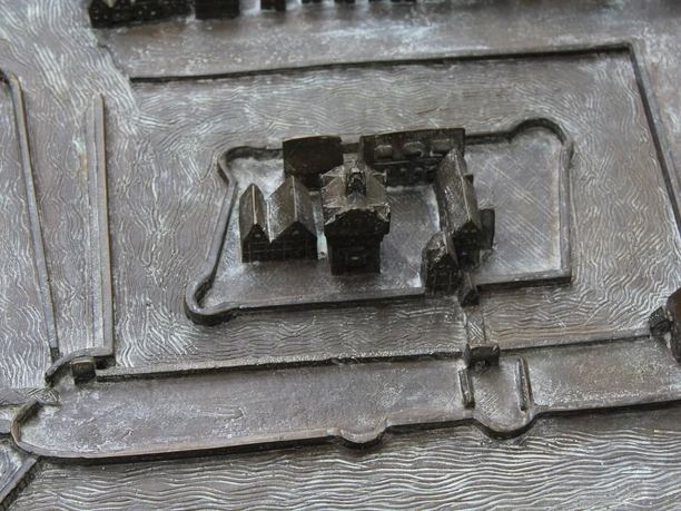 Stadtmodell Ein bronzenes Stadtmodell zeigt die historische Innenstadt mit zentralem Gebäude und umgebender Struktur.