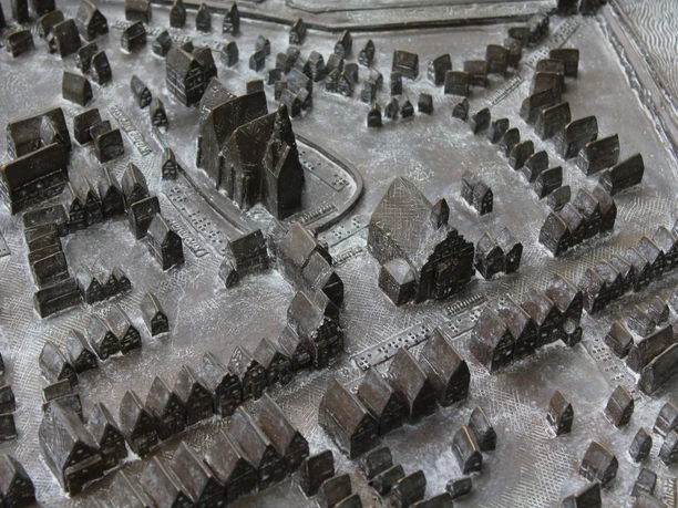 Bronzenes Stadtmodell mit detaillierten, erhabenen Gebäuden und Straßen einer historischen Stadt.