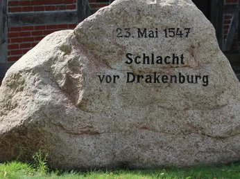 Gedenksstein an der Olen Schüne in Drakenburg Gedenkstein aus Stein mit Inschrift „23. Mai 1547 Schlacht vor Drakenburg“ auf grüner Wiese.