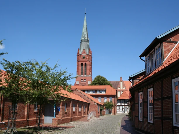 Church tower of St. Martin in Nienburg towers above surrounding brick buildings, blue sky in the background.