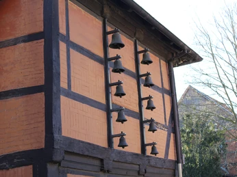 Eine traditionelle Fachwerkfassade mit 10 schwarzen Glocken, die horizontal montiert sind.