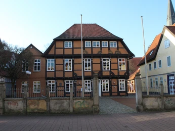 Posthof Fachwerkgebäude mit rotem Ziegeldach inmitten einer gepflasterten Straße, umgeben von weiteren Gebäuden.