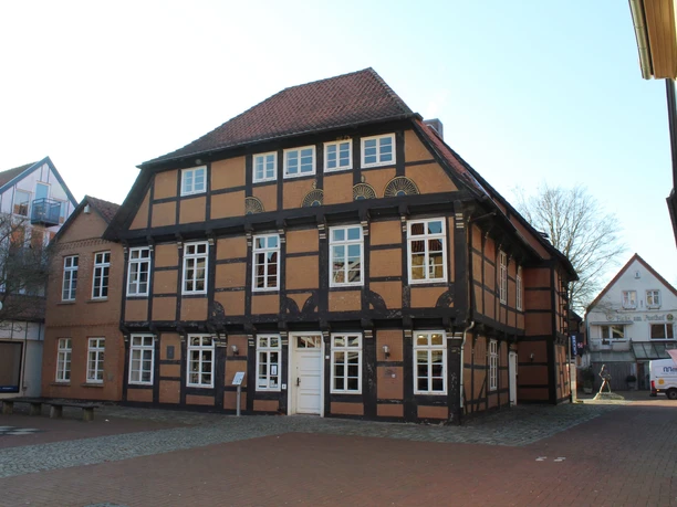 Posthof Fachwerkhaus mit rotem Ziegeldach und weißen Fensterrahmen, umgeben von gepflasterten Wegen.