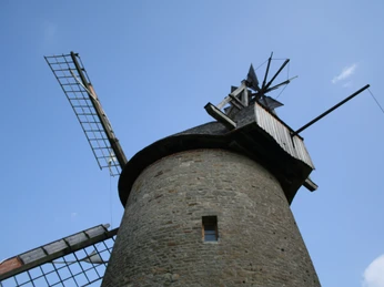 Pottmühle Petershagen Historische Steinmühle mit drehenden Flügeln gegen blauen Himmel, symbolisiert traditionelle Handwerkskunst.
